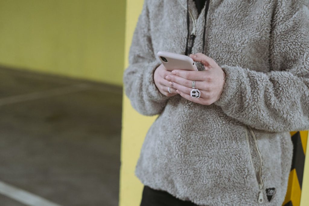 Close-up of a person texting on their smartphone with a cozy sweater in an industrial urban setting.